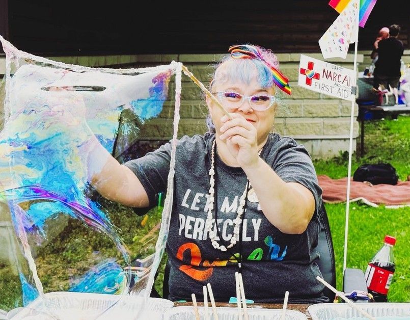 Person painting a colorful butterfly display at an outdoor craft table
