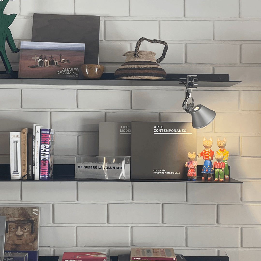 Un estante con algunos libros y una lámpara encima.