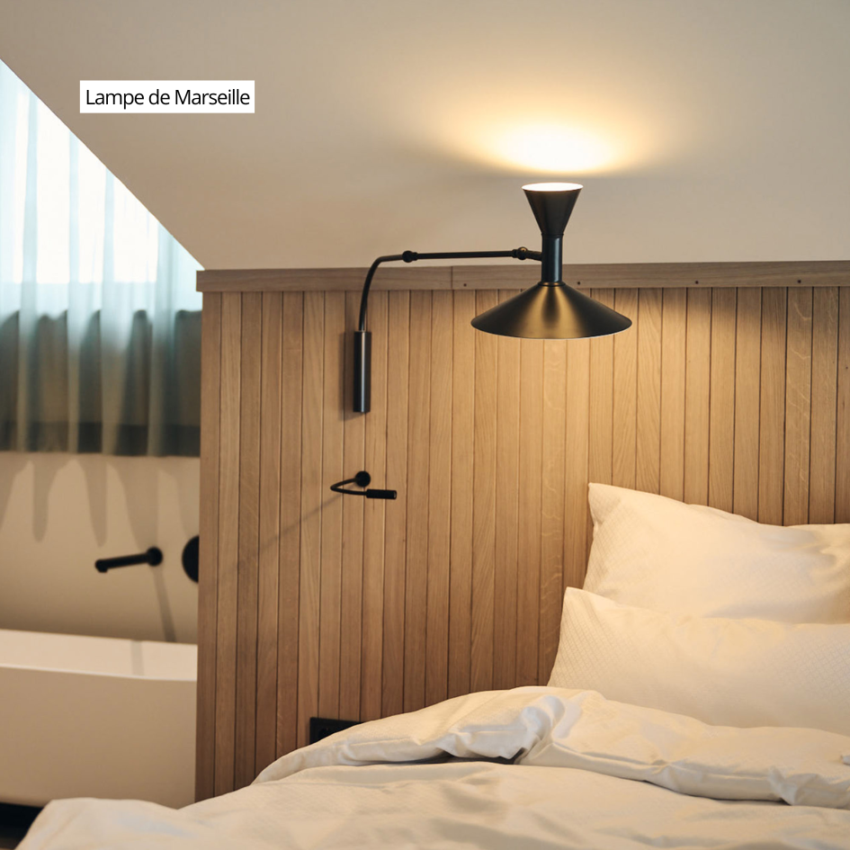 Un dormitorio con una lámpara en la pared encima de la cama.