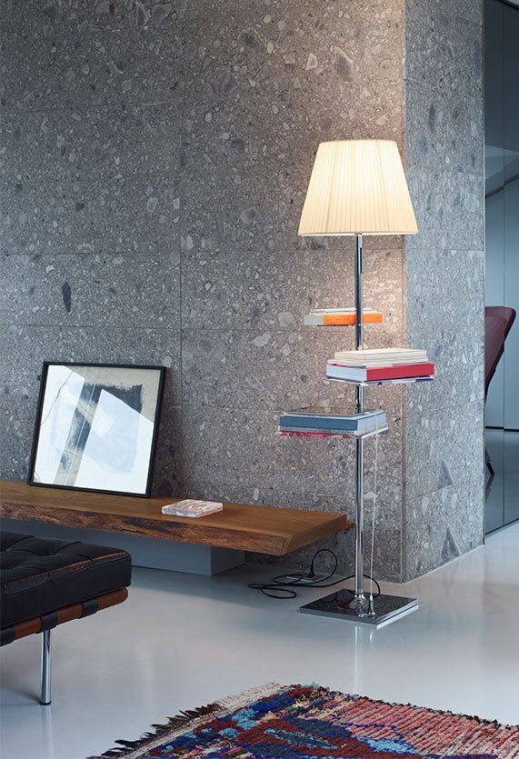 Una sala de estar con una lámpara y una pila de libros sobre una mesa.