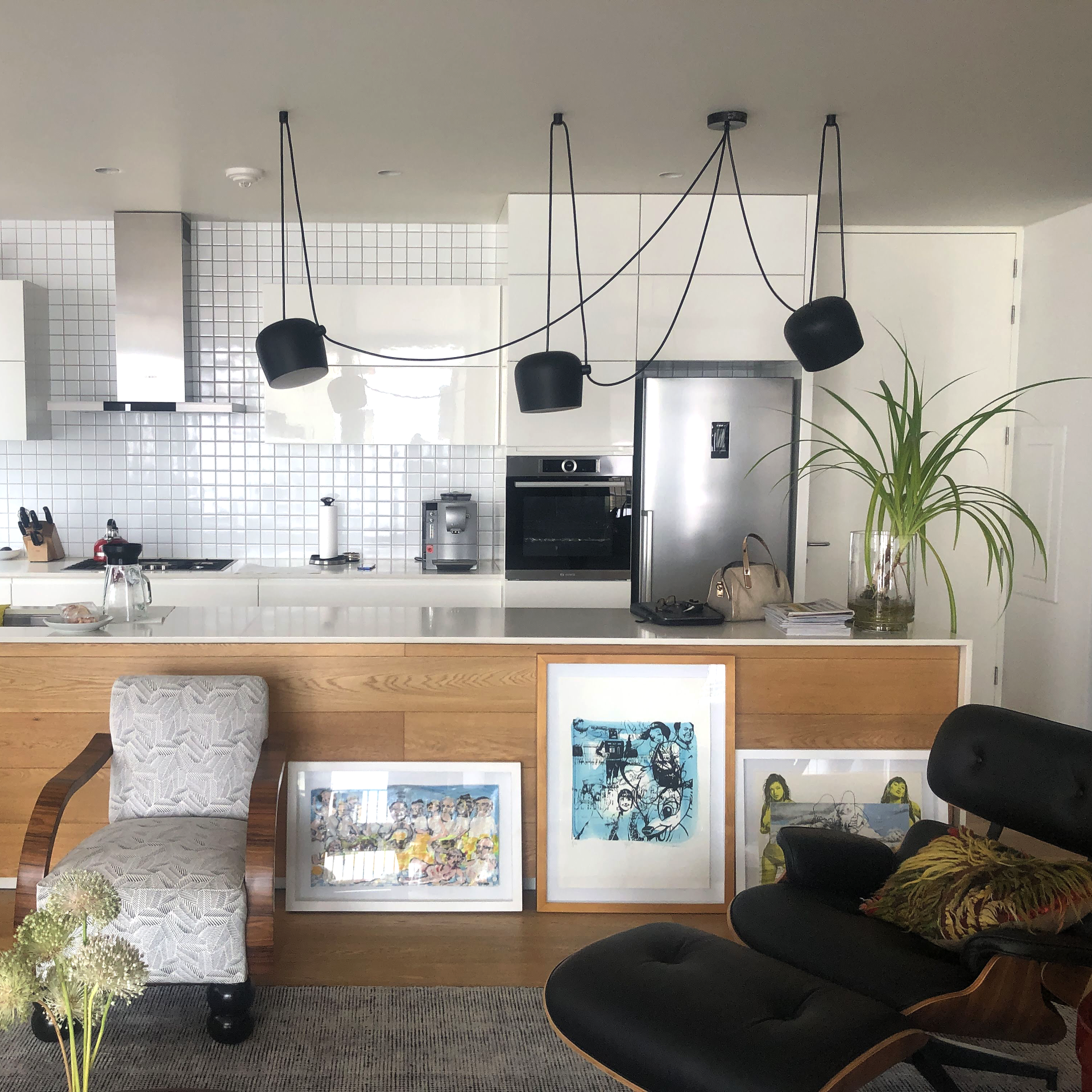 Una sala de estar con una silla y una otomana frente a una cocina.