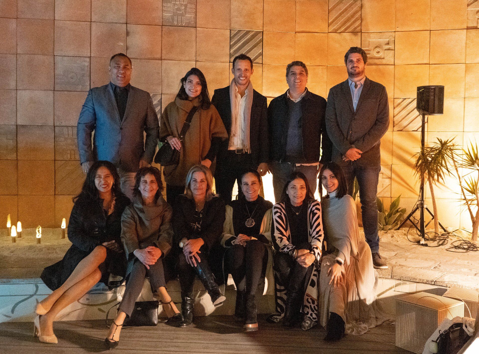 Un grupo de personas posan para una fotografía frente a una pared de ladrillos.