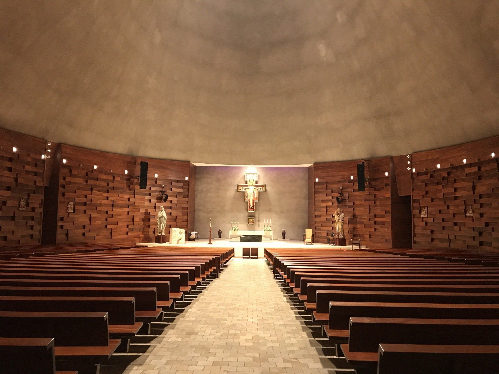 Una iglesia vacía con hileras de bancos de madera y una cruz en el altar.