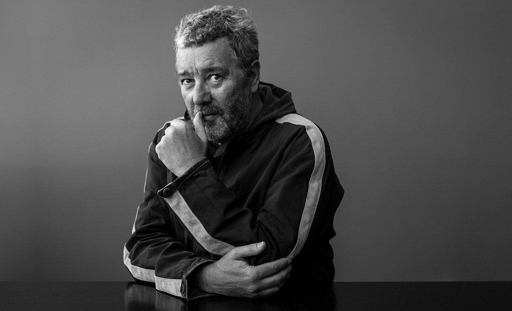 Un hombre con barba está sentado en una mesa en una foto en blanco y negro.