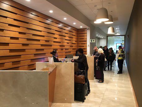 Un grupo de personas se encuentra de pie ante un mostrador en el vestíbulo de un hotel.