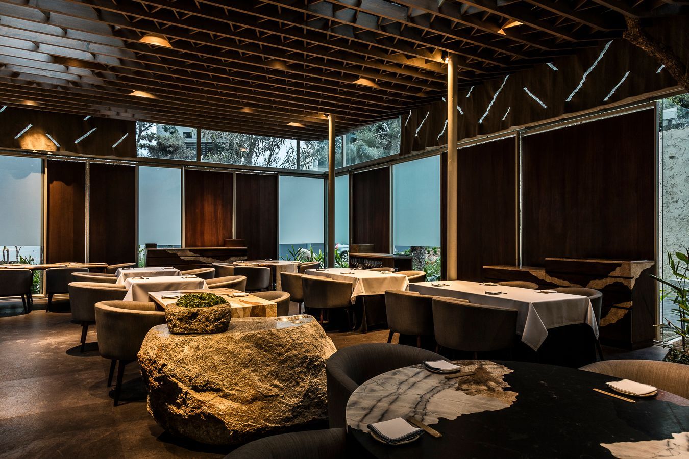 Un restaurante con mesas y sillas y una gran roca en el medio de la habitación.