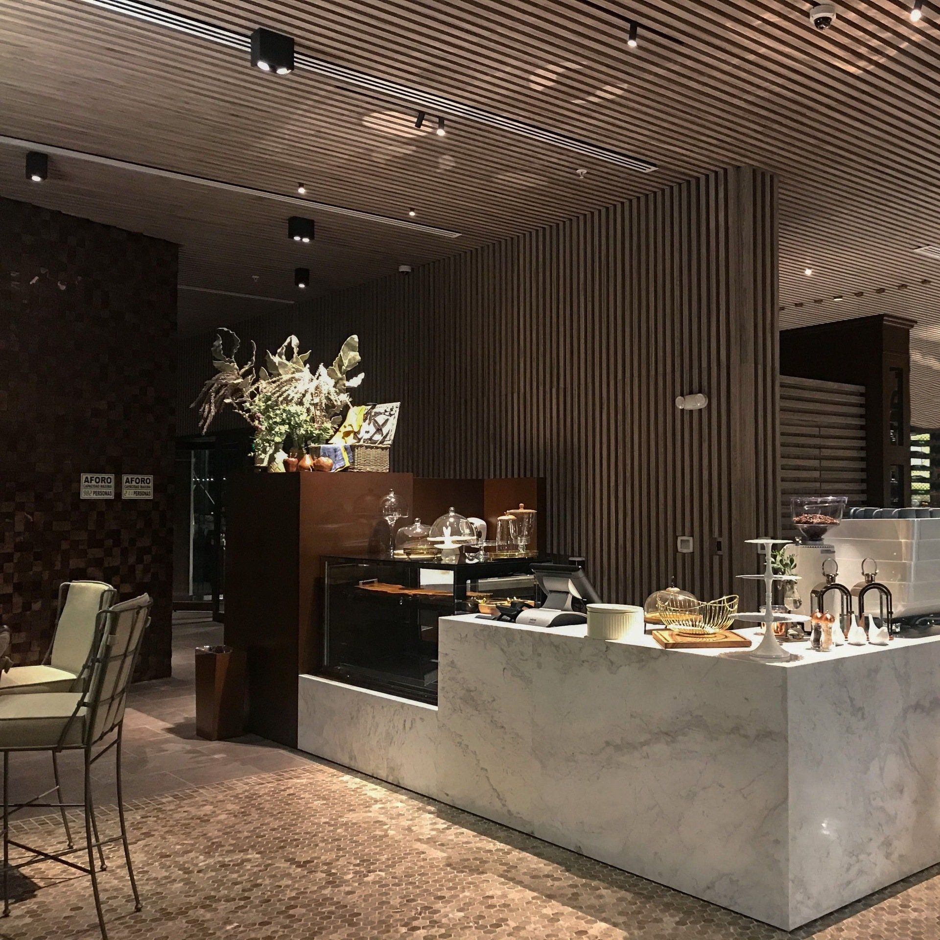 Un restaurante con mostrador de mármol, mesas y sillas.