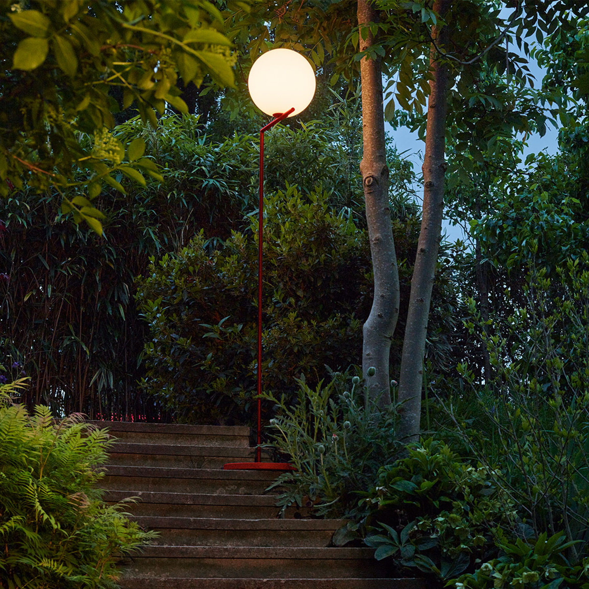 Una lámpara se enciende en unas escaleras de un jardín.