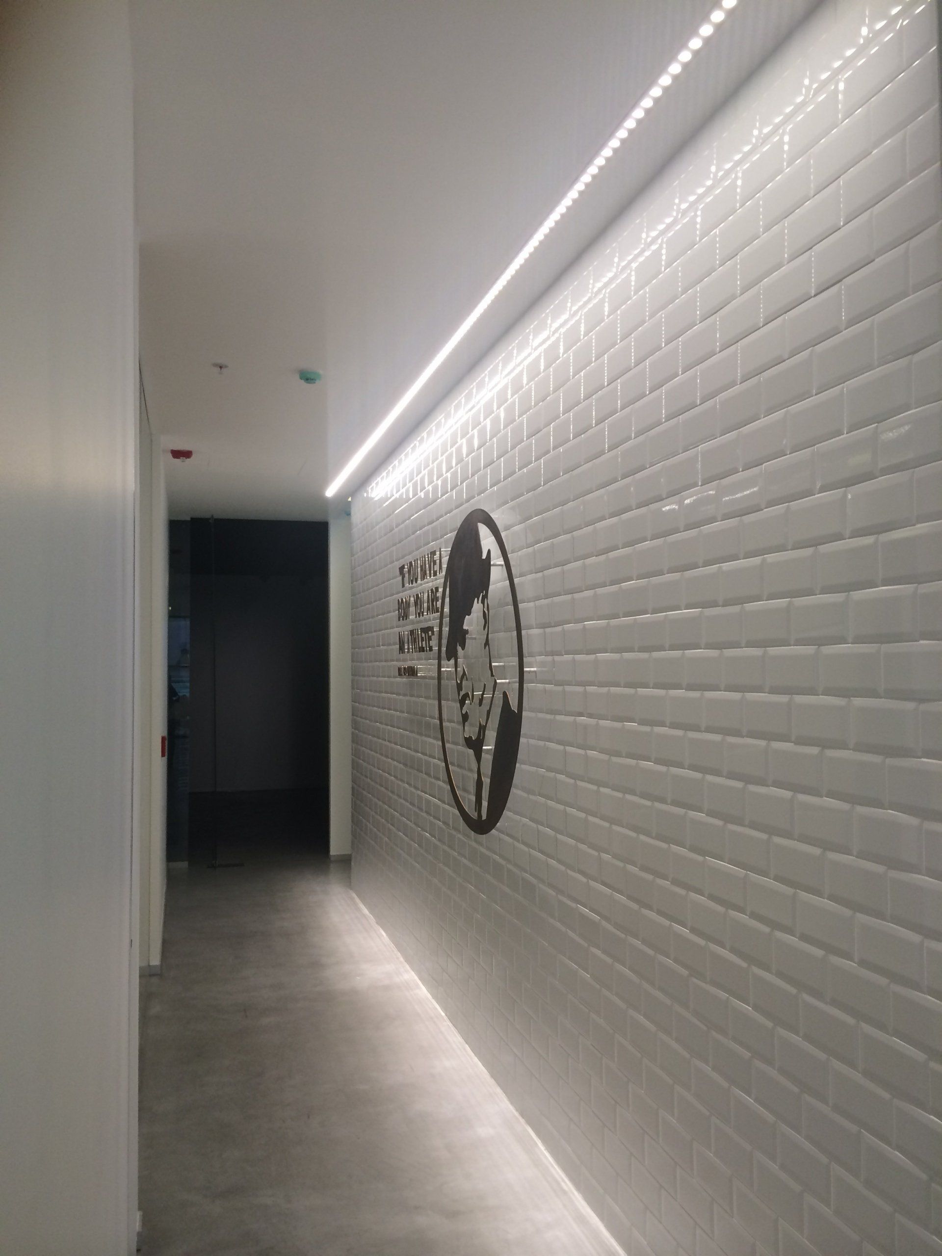 Un pasillo largo con una pared de ladrillos y un cuadro en ella.