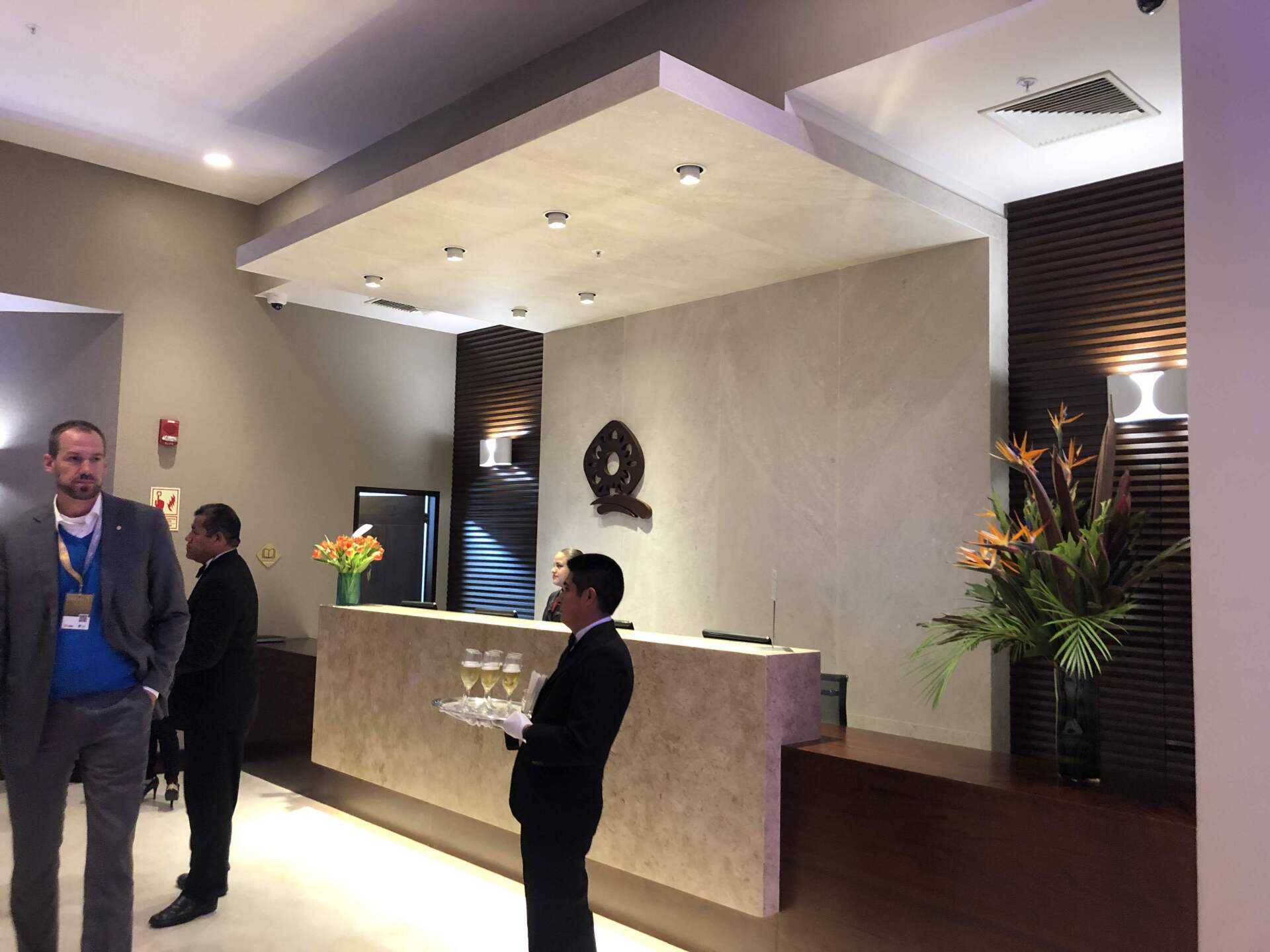 Un hombre está de pie frente a un mostrador de recepción en el vestíbulo de un hotel.