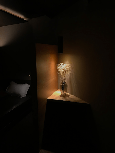 Un jarrón de flores está sobre una mesa en una habitación oscura.