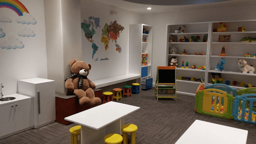 Un osito de peluche está sentado en un banco en una sala de juegos.