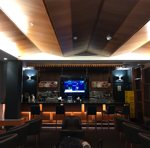 Un bar con un gran televisor de pantalla plana colgado del techo.
