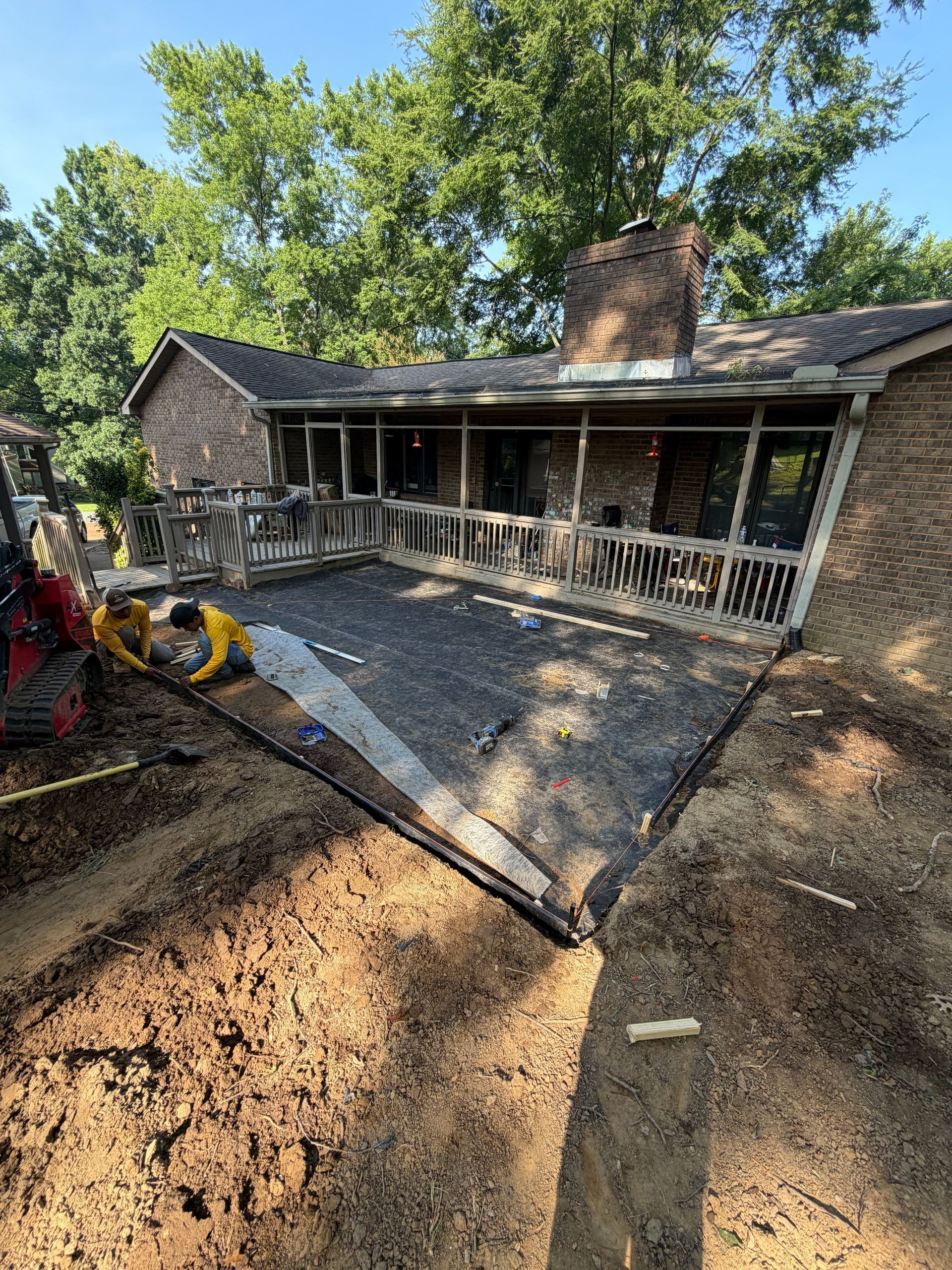 Workers installing a wooden fence in a suburban backyard with a wheelbarrow in the foreground