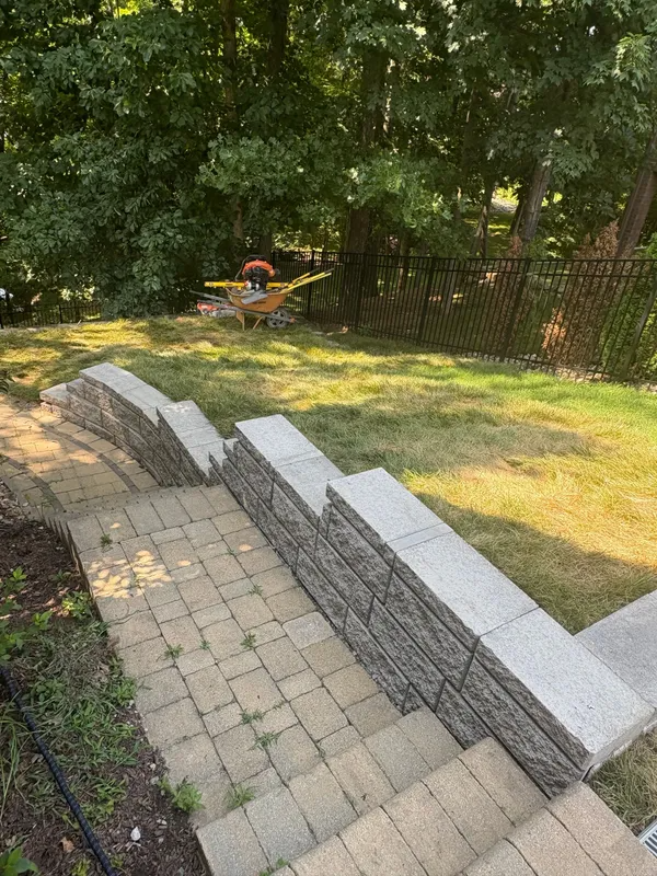 Stone steps leading to a grassy yard with a fence and trees beyond.