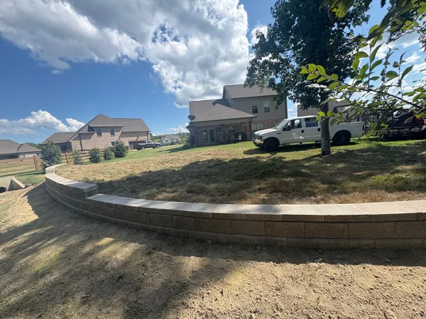Suburban homes on a sunny day, with a curved retaining wall, dry yard, and a white pickup truck.