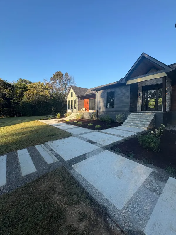 Modern house with stone walkway, lawn, and clear blue sky