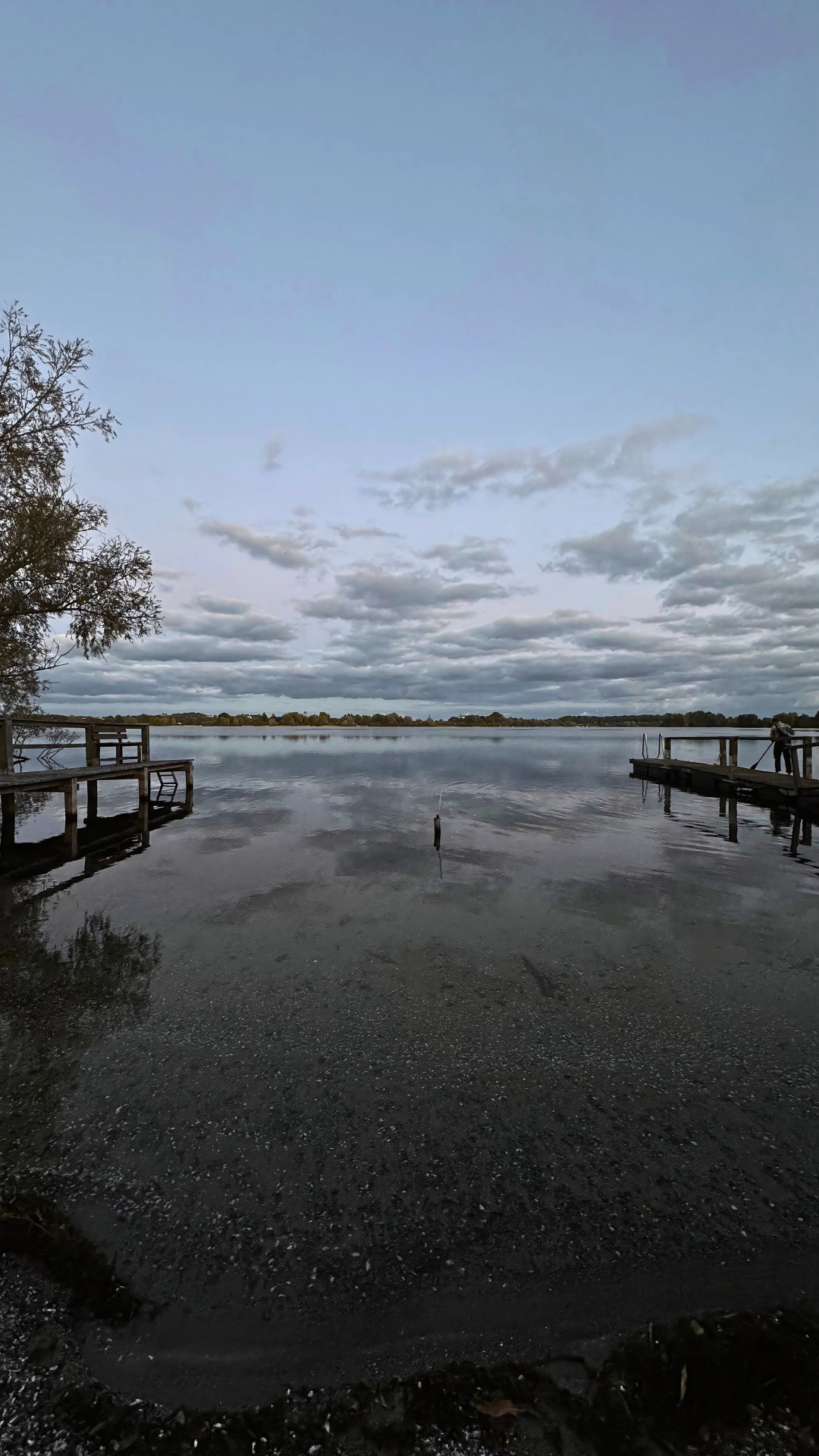 kleiner Plöner See mit zwei Holzstegen rechts und links im Sonnenuntergang