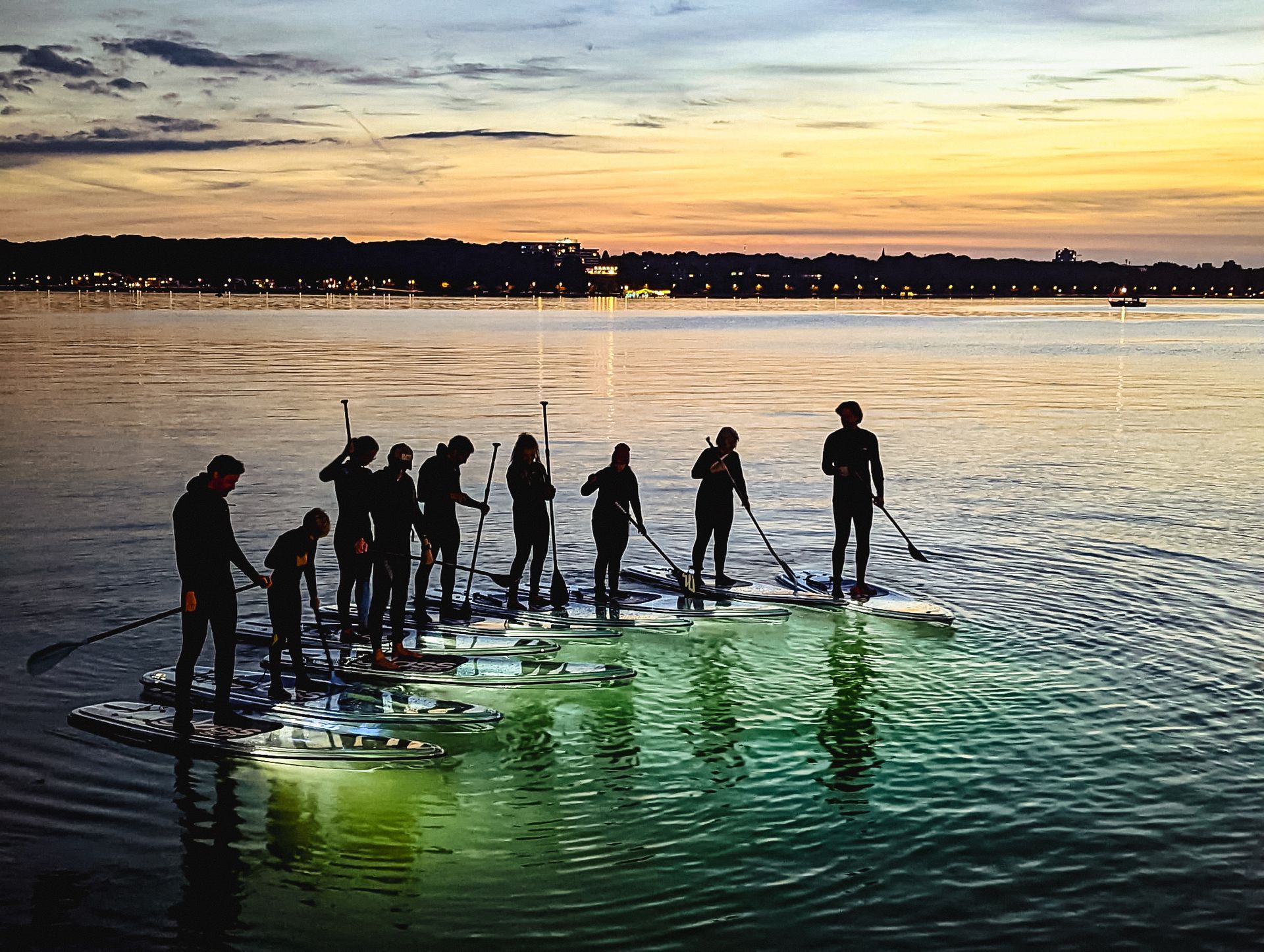 Eine Gruppe von Menschen steht auf glassSUPs im Wasser.