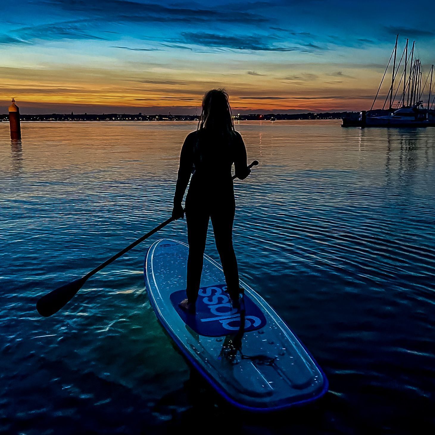 Eine Frau steht auf einem durchsichtigen Paddleboard im Wasser