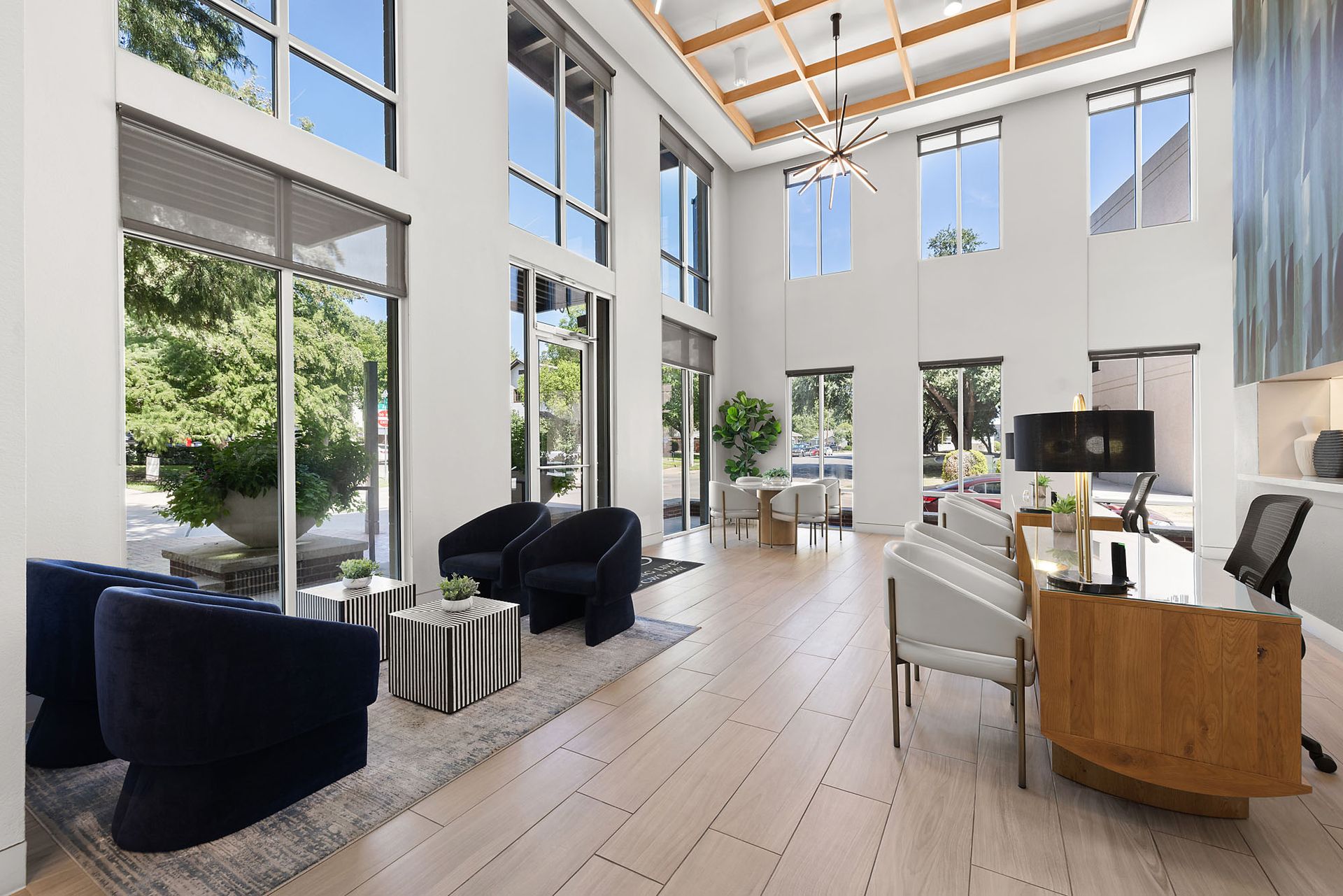 Bright modern living room with tall windows, black chairs, light wood floors, and a TV console at Marq on West 7th.