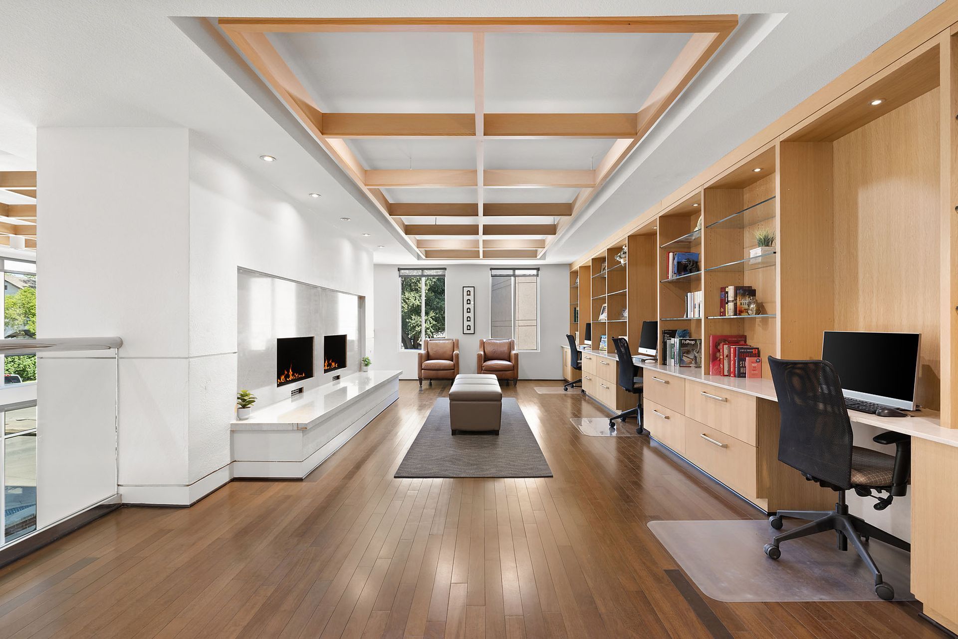 Modern open-plan office with wood floors, desk stations, and a wall-mounted TV at Marq on West 7th.