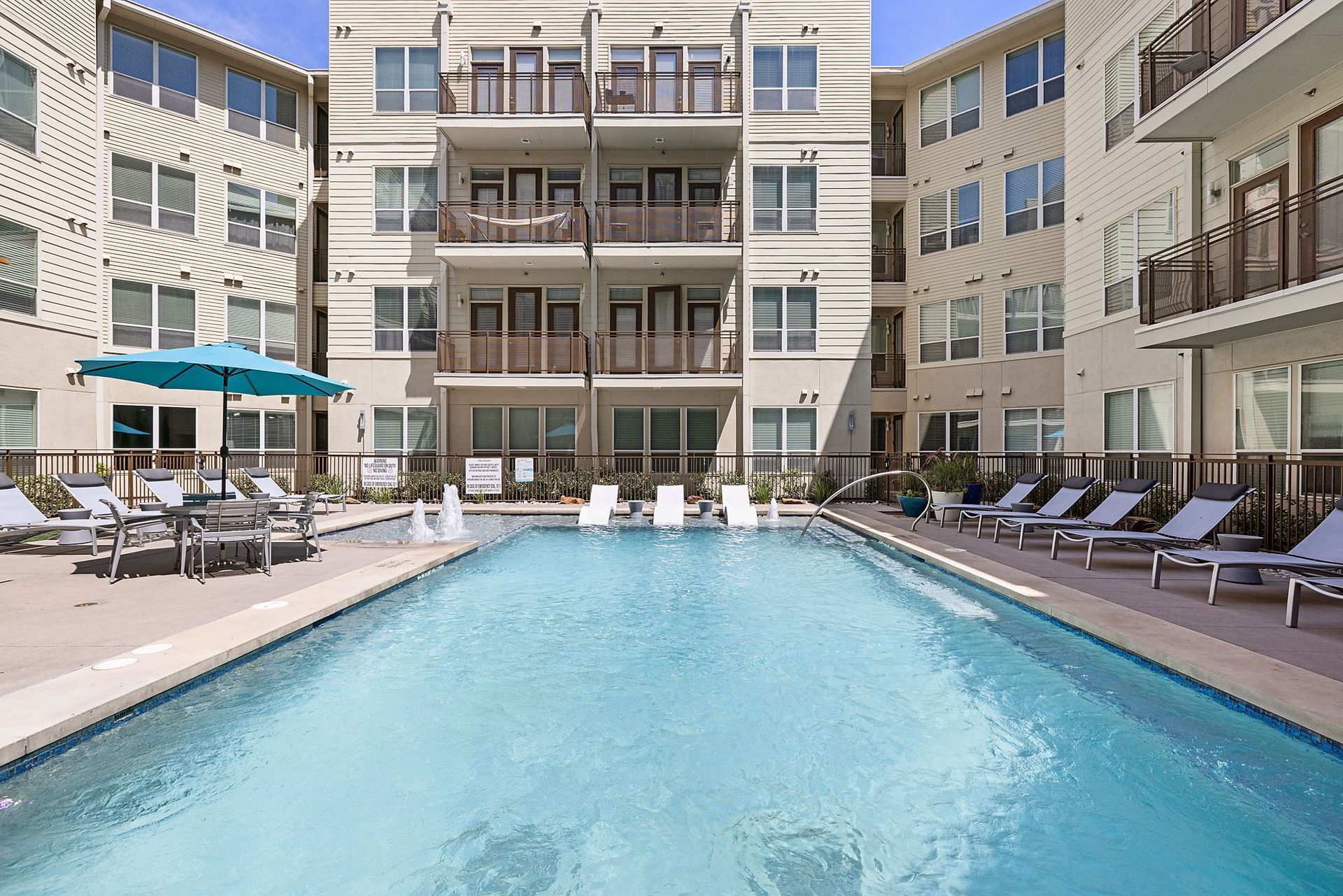 Apartment courtyard pool with lounge chairs and balconies surrounding the water