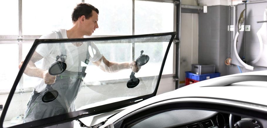 Person washing a car window with a squeegee inside a garage