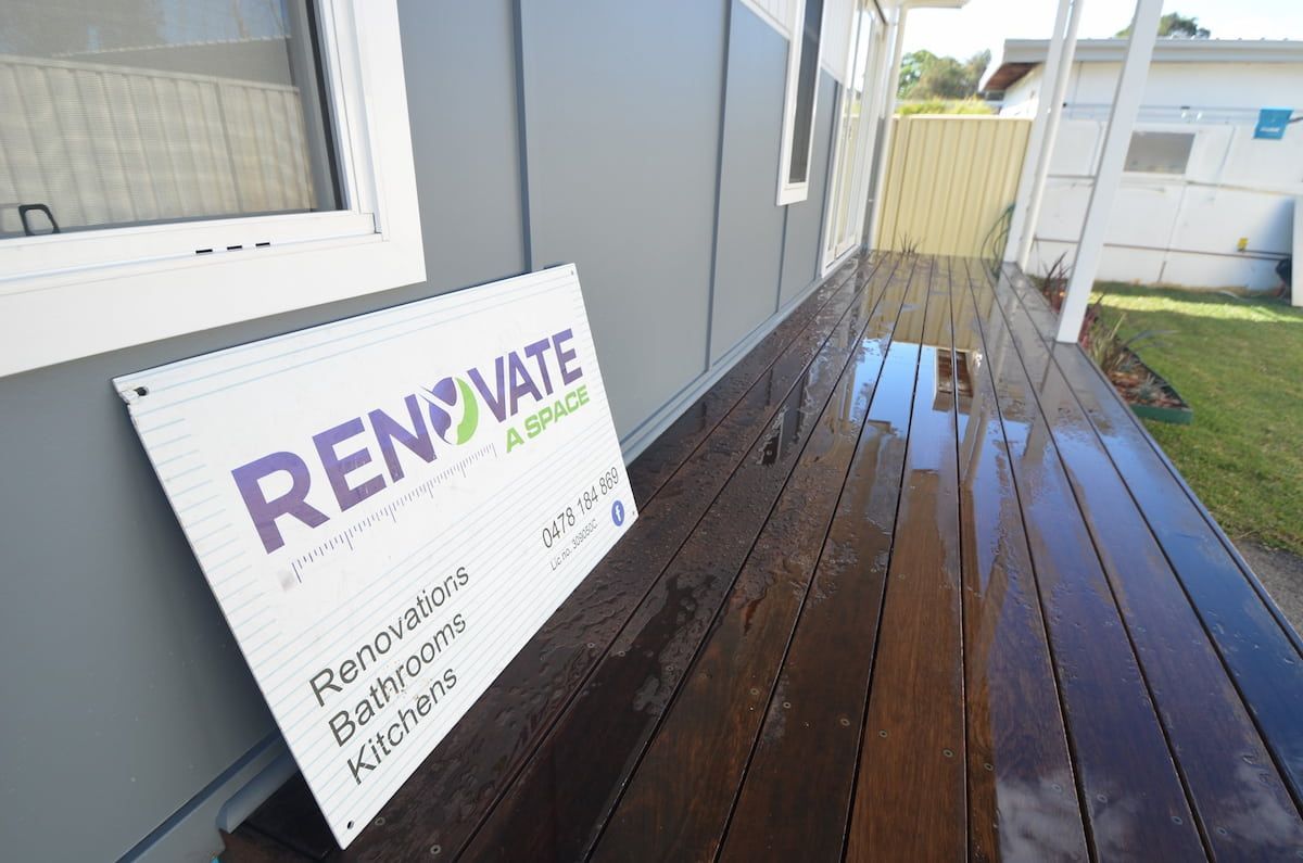Renovate Sign Is On A Wooden Deck In Front Of A House — Renovate A Space In Empire Bay, NSW