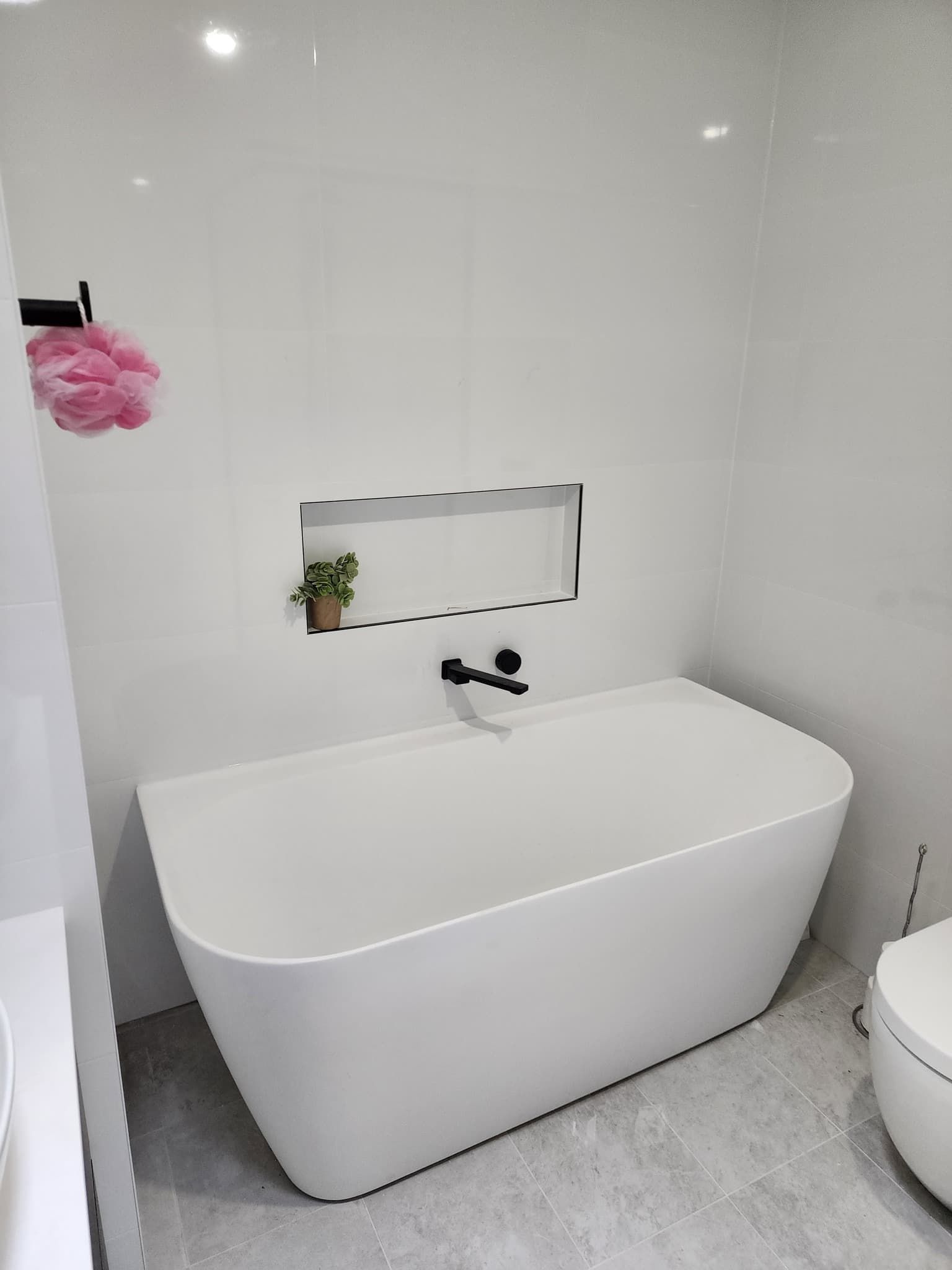 A White Bathtub Is Sitting In A Bathroom Next To A Toilet — Renovate A Space In Empire Bay, NSW