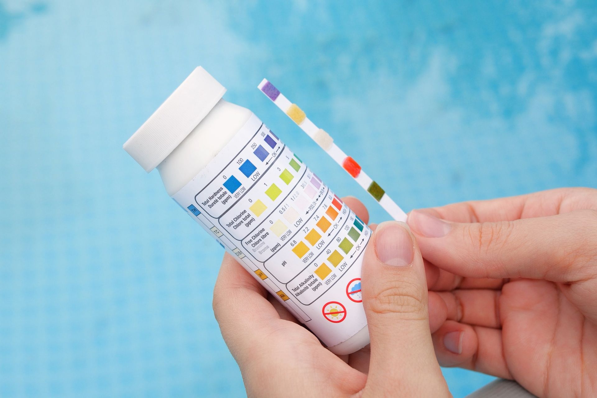 Hands holding a urine test strip bottle against a blue background