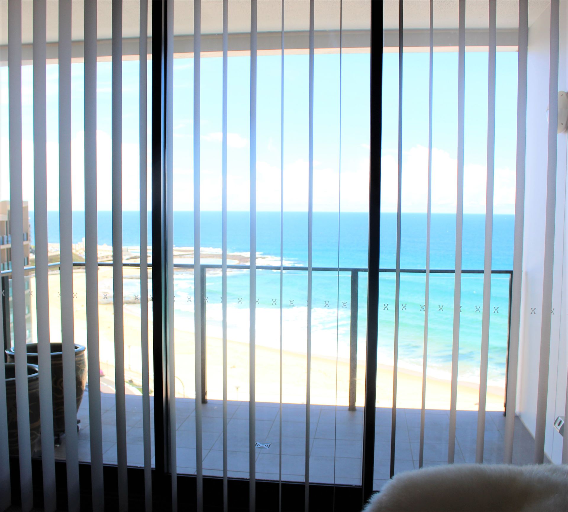 custom blinds on a window overlooking the beach - Maxview Blinds & Shutters