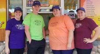 A group of people standing next to each other in front of a restaurant.