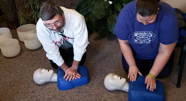 A man and a woman are doing a cpr on a mannequin