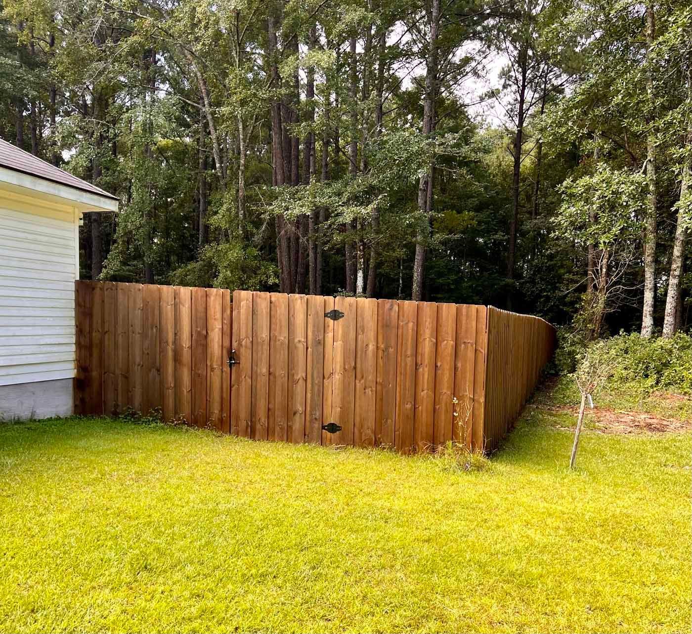 A wooden fence is in the backyard of a house.