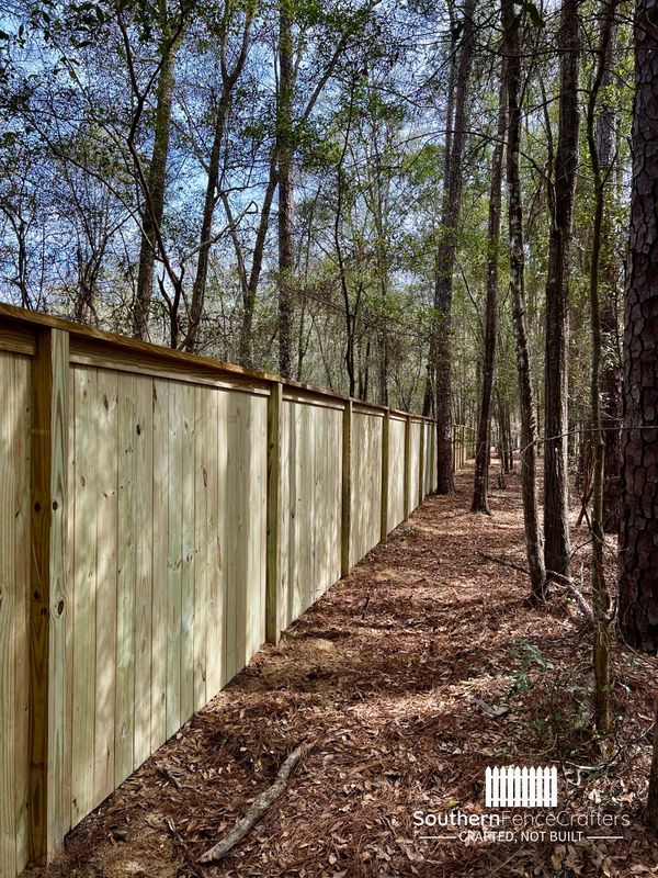 A wooden fence is surrounded by trees in the middle of a forest.