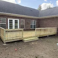 Wooden accessibility ramp leading to a brick building's French doors and windows