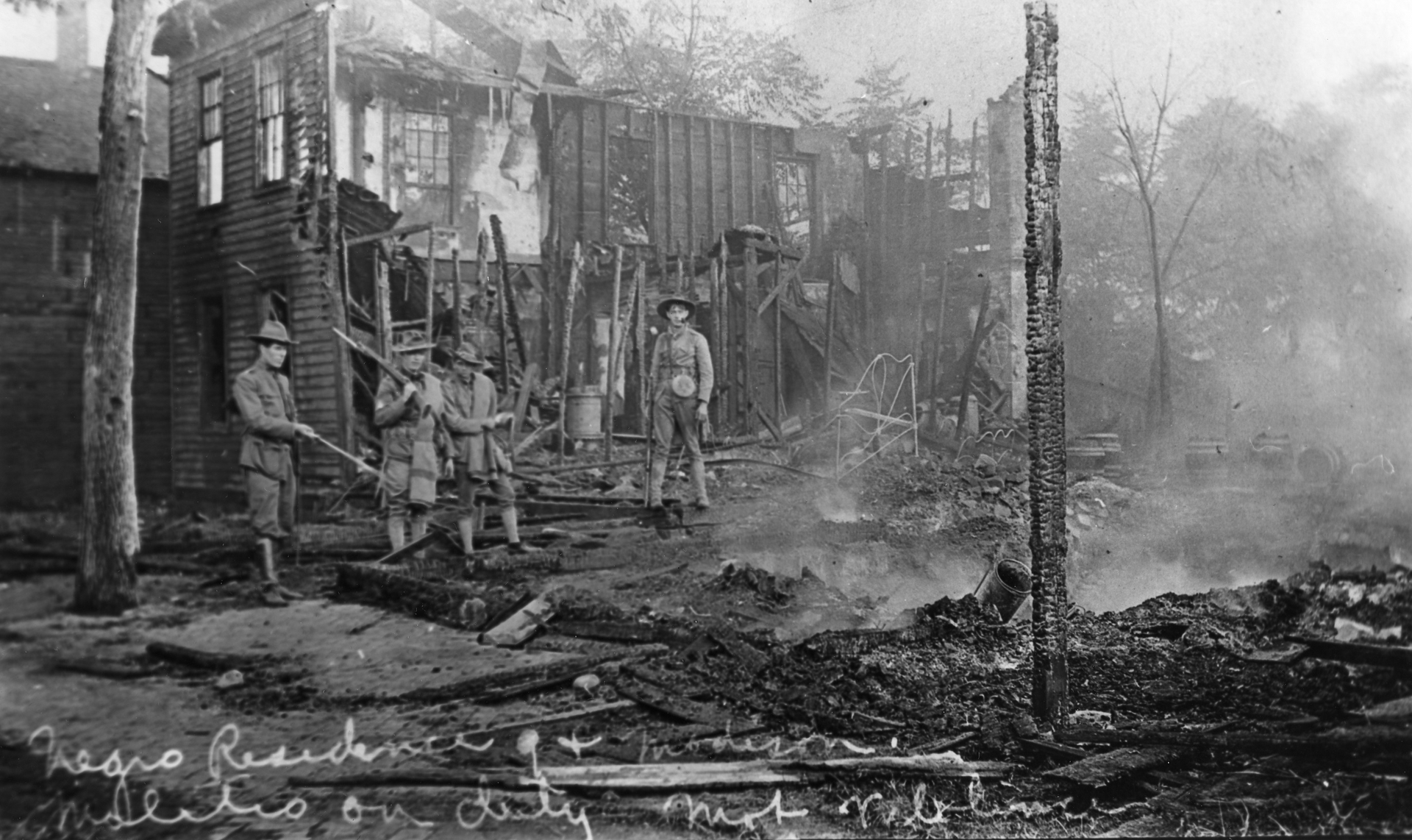 Black and white photograph of national guard soldiers standing in a burned out residence during the Springfield, IL race riot of 1908.