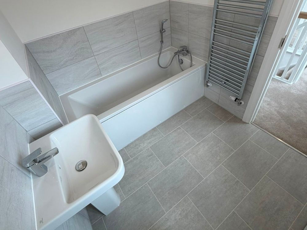 Fitted bathroom with bath, basin, chrome heated towel rail and tiled floor