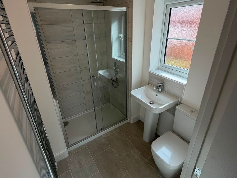 Fitted bathroom with sliding door shower enclosure, tiled walls and floor