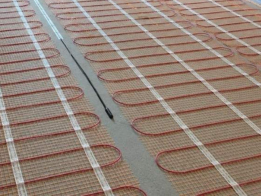 Close-up of heating cable looped across a mesh mat, with a black lead laid between two mats