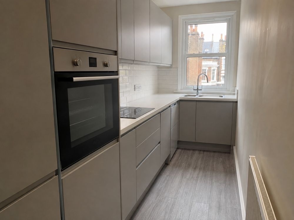 Narrow galley kitchen with grey slab units and metro tile splashback in a Victorian terrace