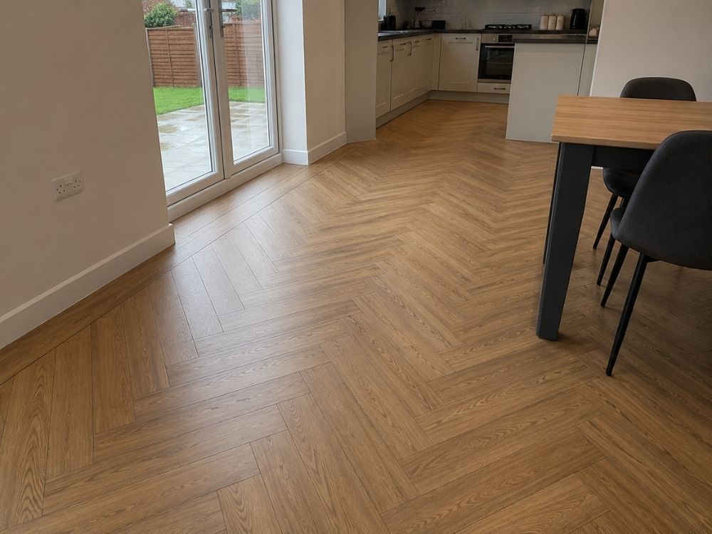 Herringbone luxury vinyl tile flooring in a warm oak effect laid in an open-plan kitchen diner