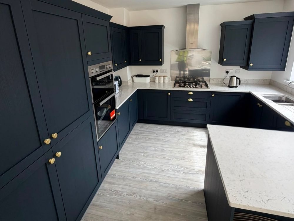 Navy kitchen with full-height oven housing, brass handles and quartz worktop