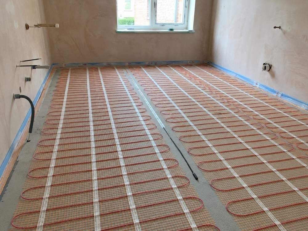 Electric underfloor heating mat rolled out on a primed subfloor before tiling