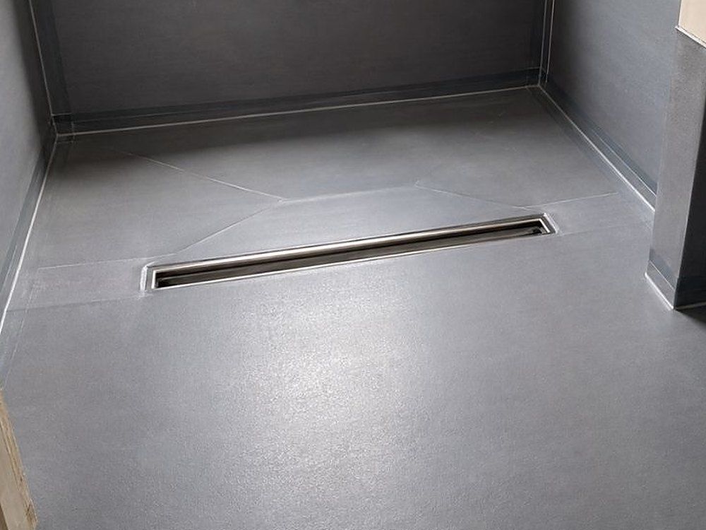 Wet room floor and walls tanked in grey membrane, with a linear drain set into the falls