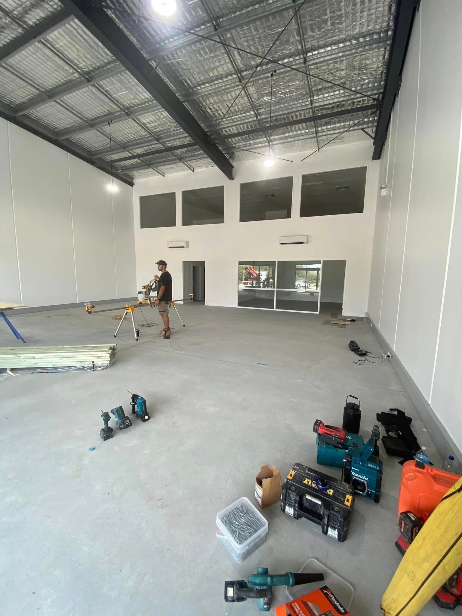 Large Empty Warehouse Interior With Tools on the Floor — Tyrone Building Solutions in Anna Bay, NSW