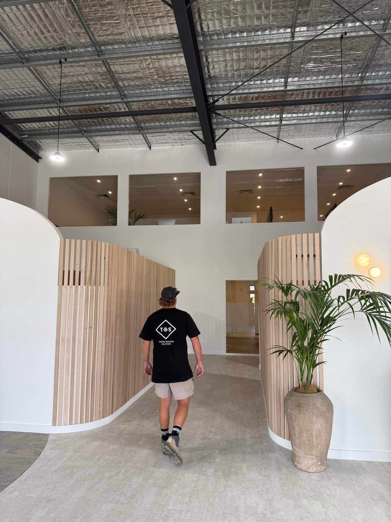 Person Walking Into a Modern White Interior With Wood Accents — Tyrone Building Solutions in Anna Bay, NSW