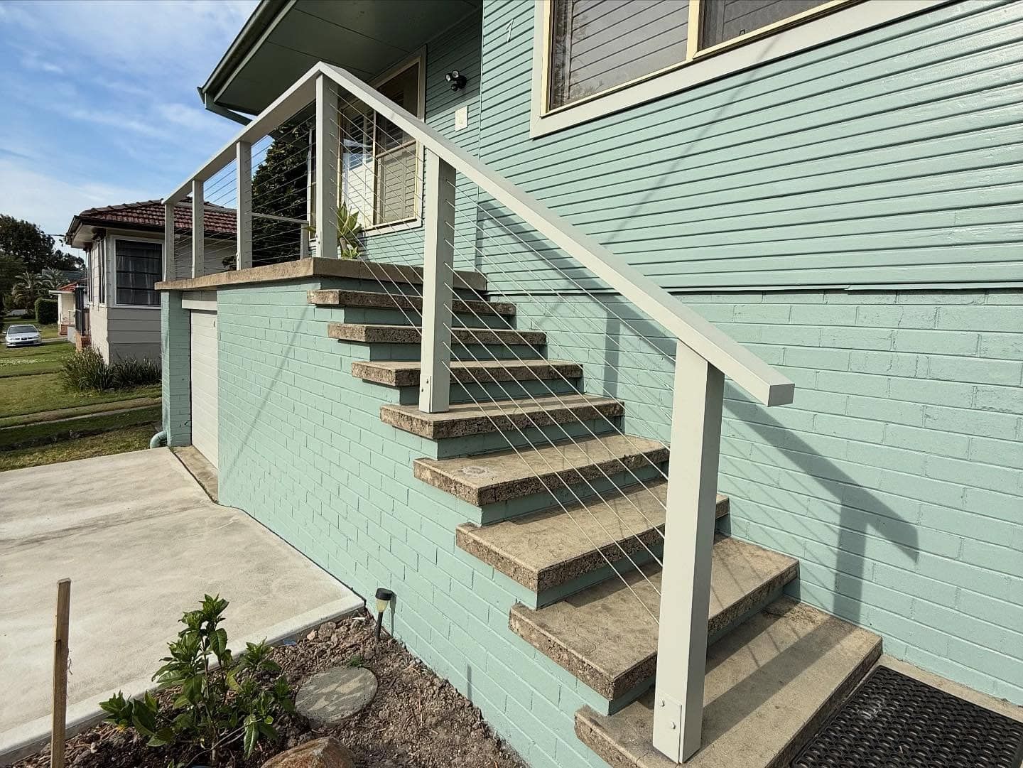Mint-green house exterior with concrete stairs and white handrails leading to the porch — Tyrone Building Solutions in Anna Bay, NSW