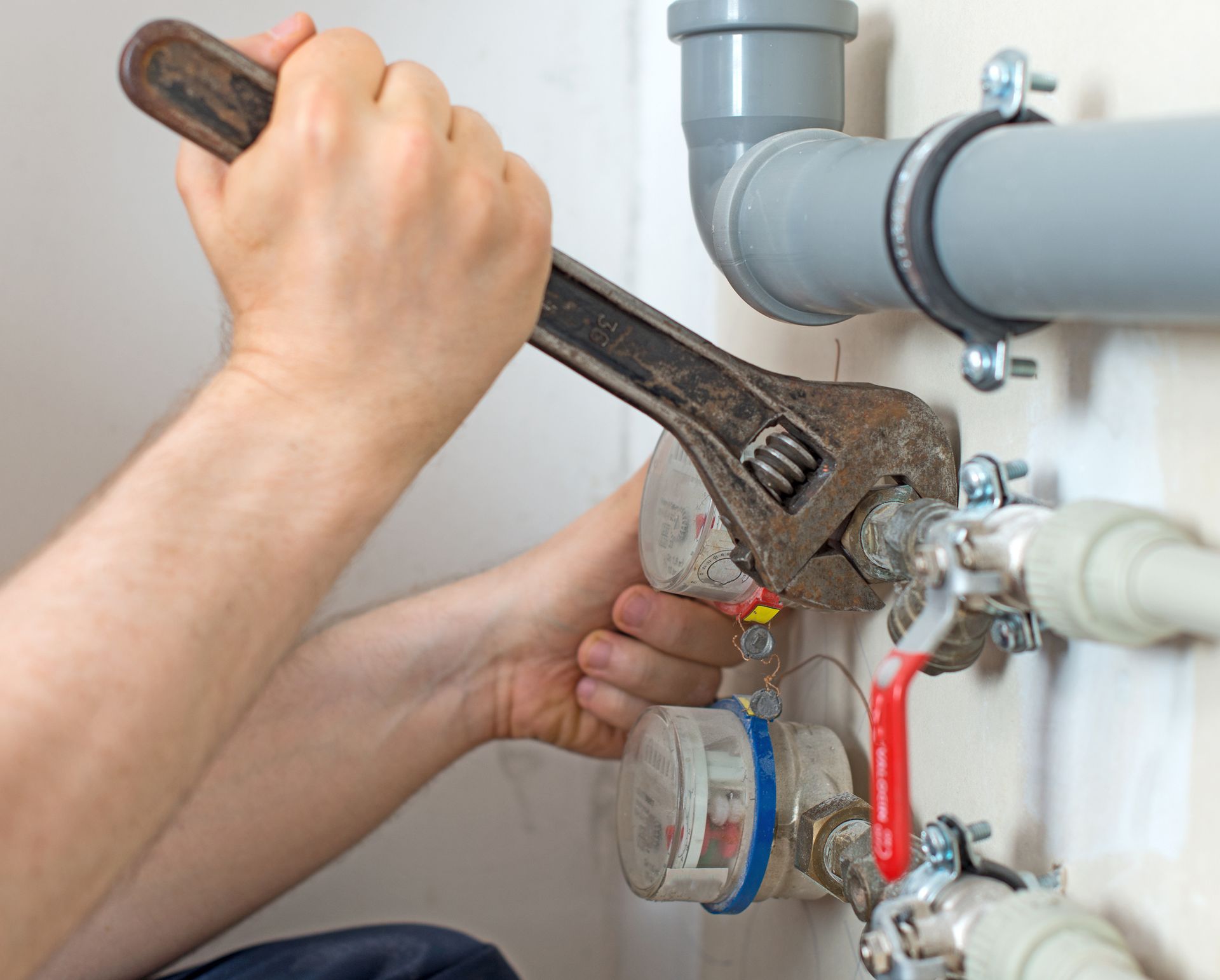 Plumber tightening residential pipes with wrench – expert plumbing repair and maintenance service.